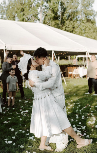 Couple kissing under petals in front of the reception tent